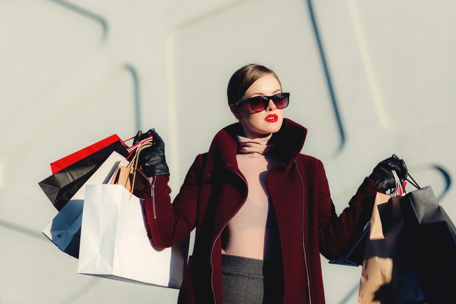 A shopper in a red coat carrying an armful of shopping bags